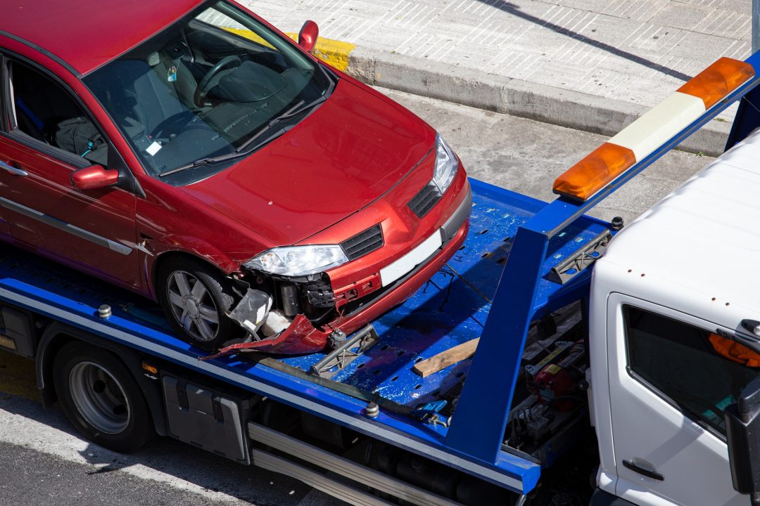 Crashed car loaded on Towing & Recovery Service tow truck. Swift recovery and transportation services for damaged vehicles.